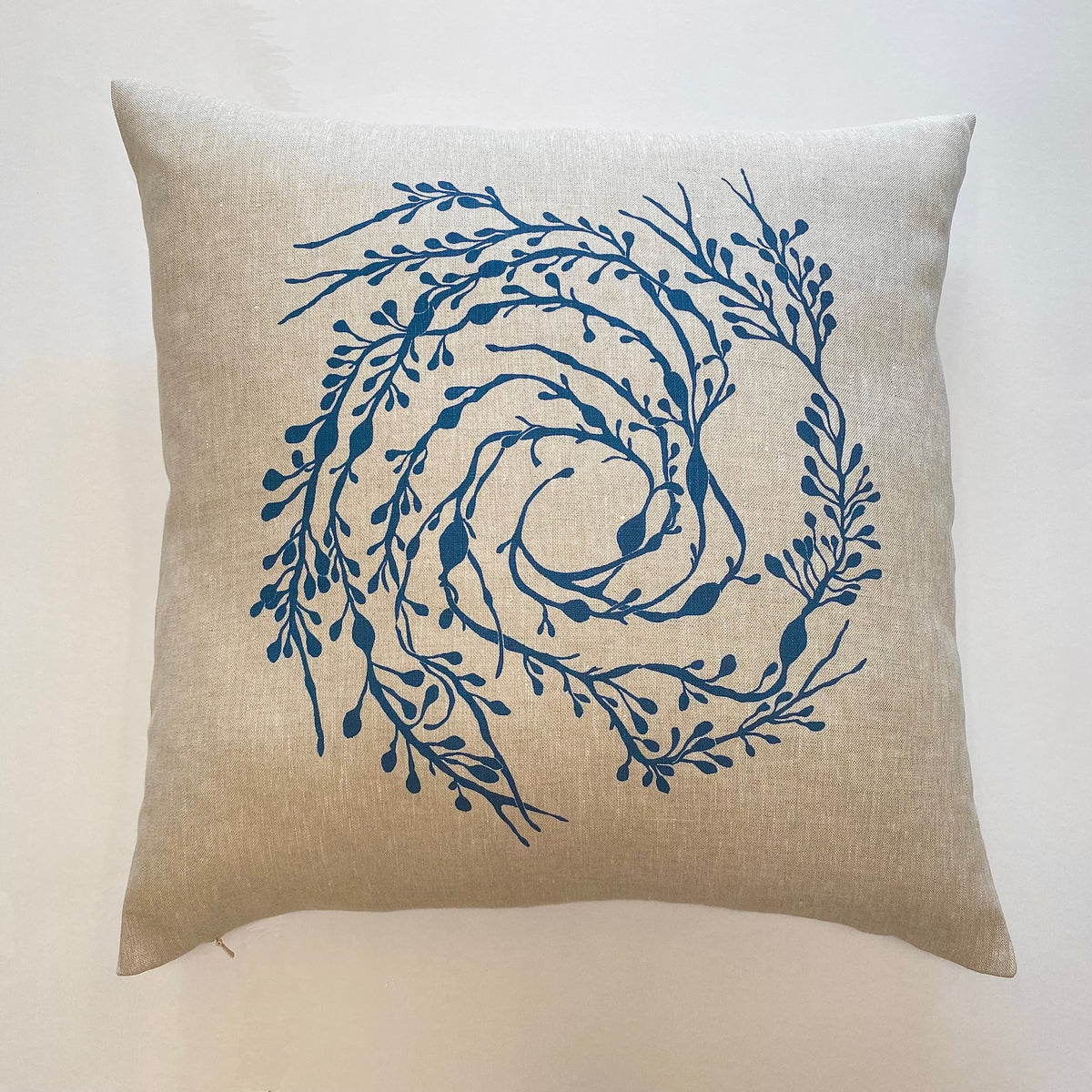 A handprinted linen cushion with a swirling Seaweed pattern design